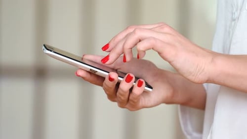 Woman's Hands Using Smartphone with Red Nail Polish