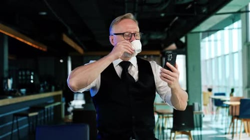Man Drinking Coffee on Video Call in Office