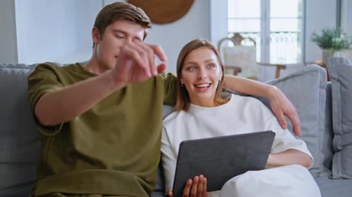 Young Couple Using Tablet on Sofa Together
