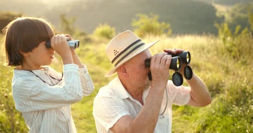 Young Boy in a Field Looking Through Binoculars