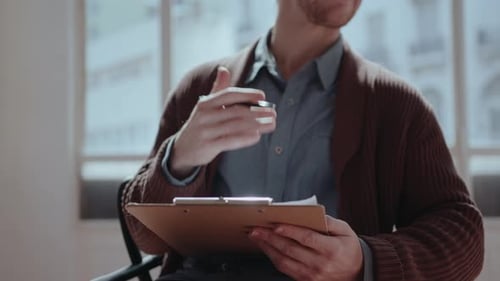 Man Gesturing with Pen While Sitting