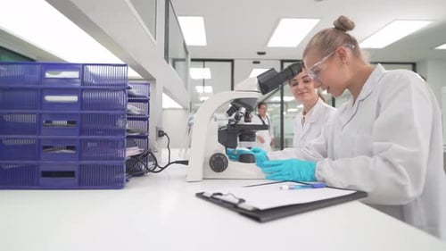 Woman uses microscope in modern, bright laboratory