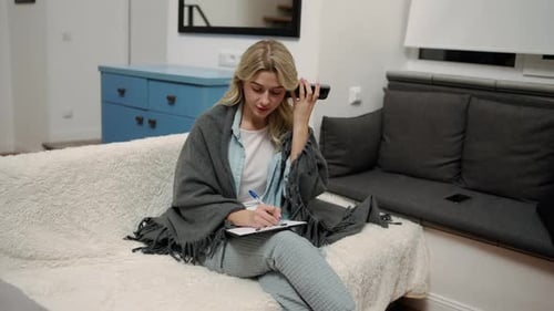 Woman Talking on Phone and Writing at Home