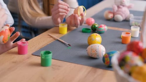 Une famille heureuse peint des œufs pour Pâques. Ils sont habillés d'oreilles de lapin