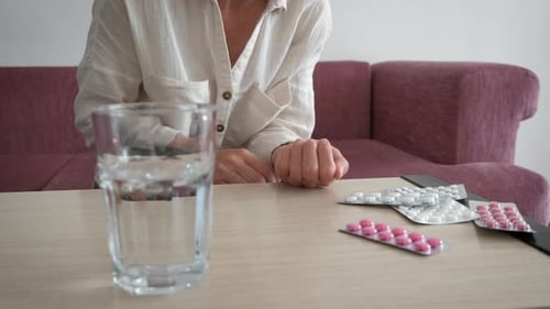 Woman with Pills and Water Ready to Take Medication