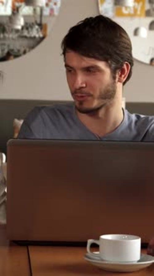 Friends Gather Around a Laptop Sharing Laughter at a Cozy Cafe