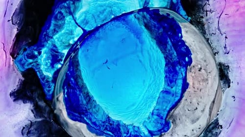 Bright blue liquids swirl and mix in a shot of artistic fluid reaction