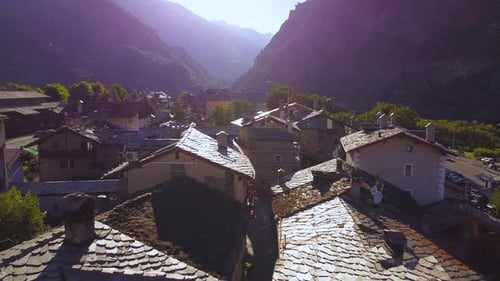Italian alps village next to mountains, closing aerial drone shot with backwards motion