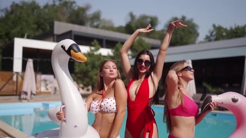 Women Models in Bright Colorful Bikinis and Sunglasses Posing at Swimming Pool Turquoise Water with