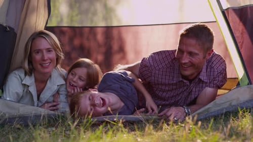 Happy family camping together in a tent on summer vacation in the countryside