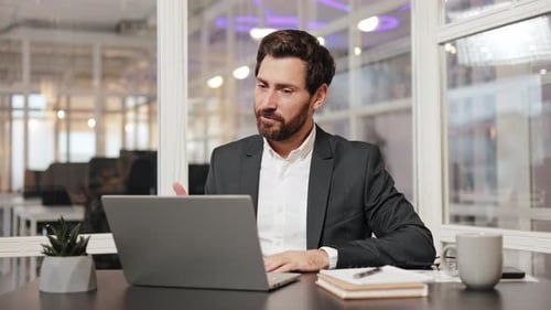 Businessman in Modern Office on Video Call Smiling and Gesturing