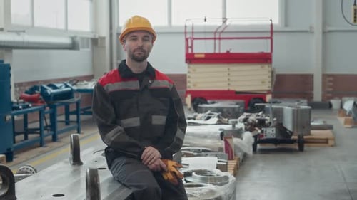 Portrait of Male Factory Worker Sitting on Workbench