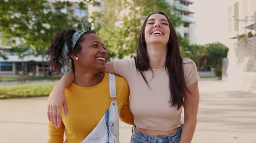 Two Happy Multiracial Women Laughing Together While Walking in City Street