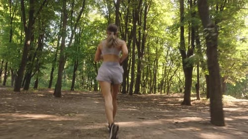 Woman Trail Running In Forest