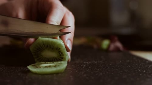 Slicing a Juicy Green Kiwi on a Black Cutting Board