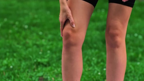 Woman Stretches Leg Muscle in Green Nature Setting