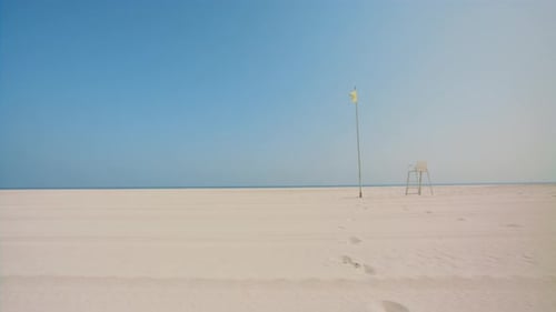À l'approche d'une mer bleue, de l'océan, marche sur du sable blanc avec une ambiance agréable, passage d'un poste de sauveteur