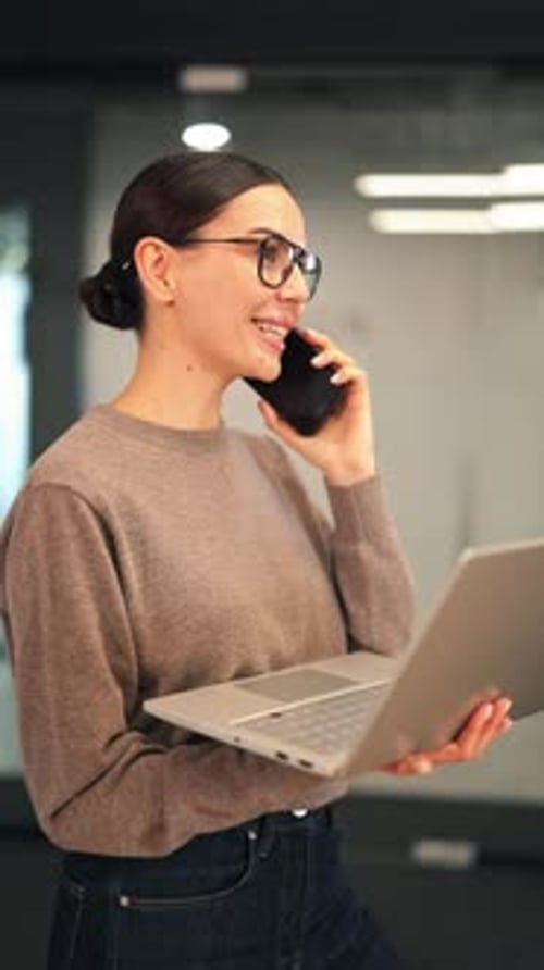 Happy Businesswoman Multitasking Communicating on Phone and Laptop in Office
