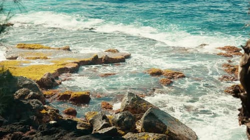 Ocean waves crashing on rocky shoreline with moss-covered stones — coastal view