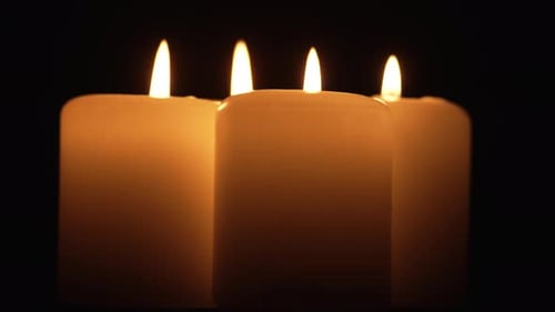 Four Big Yellow Candle Flame Burning and Rotating on Dark Background Close Up