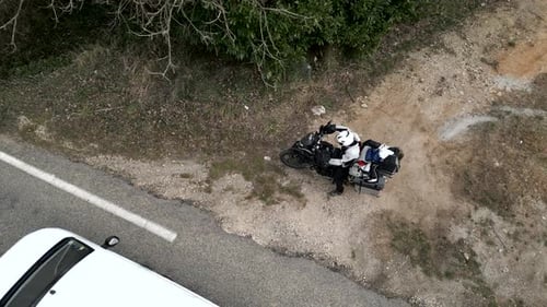 Zenithal Shot From a Drone View of a Traveling Motorcyclist Starting the Motorcycle and Starting Off