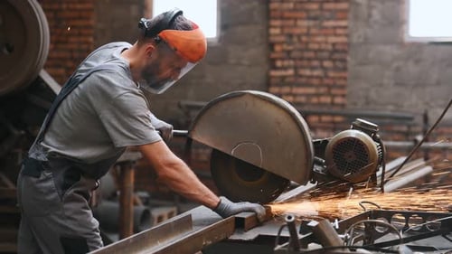 worker cuts metal on a circle and a circular saw. steel pipes and cylindrical blanks for welding.