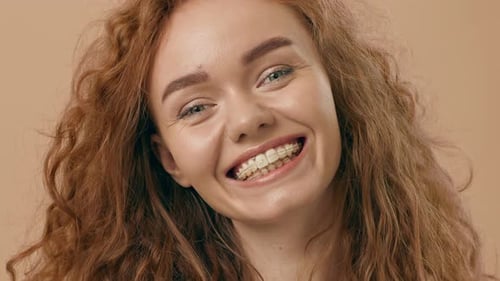 Smiling Young Woman with Curly Hair Against a Warm Background in a Studio