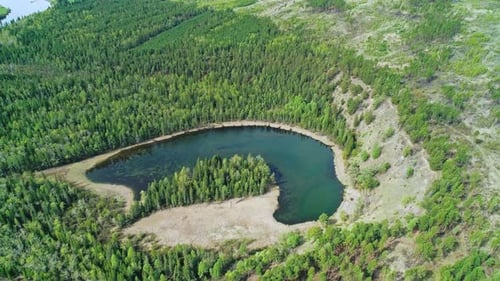 Aerial Over a Little Lake with Crystal Clear Water Surrounded with Evergreen Pine Forest on a Bright