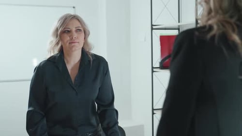 La vendedora presenta un modelo clave de Near Building mientras el cliente lo acepta con un apretón de manos