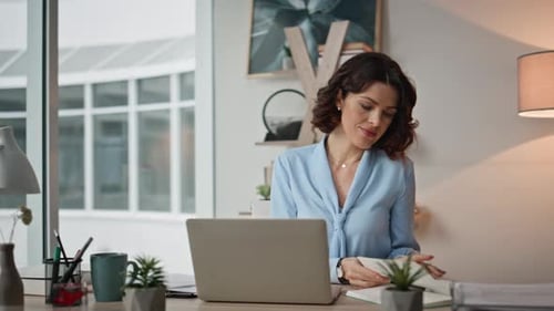 Multitasking Woman Working Office Desk with Laptop Reading Notebook Closeup
