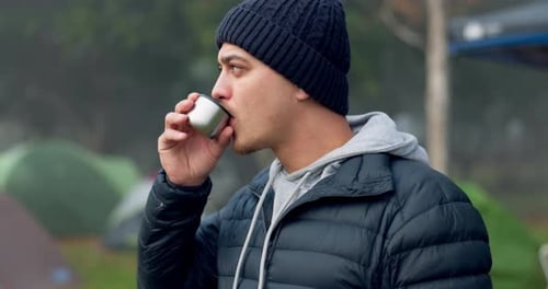 Young Man Drinking From Thermos Near Tents