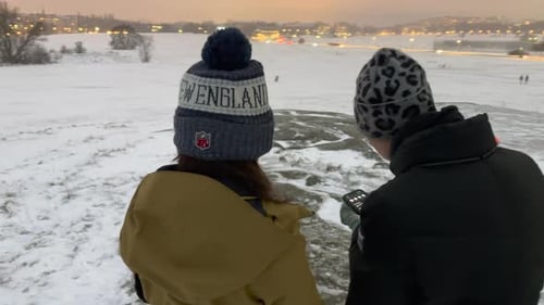 Two girls looking at their phones in a snowy landscape