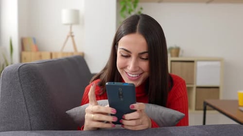 Smiling Woman Using Phone on Couch Indoors