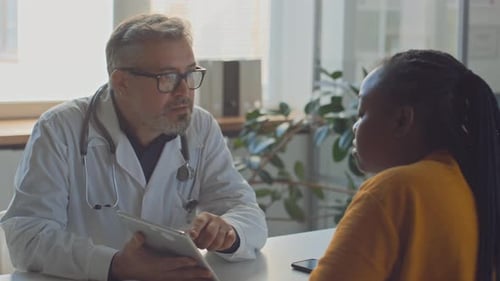 Diverse Male Doctor and Female Patient Discussing Bloodwork Results in Clinic
