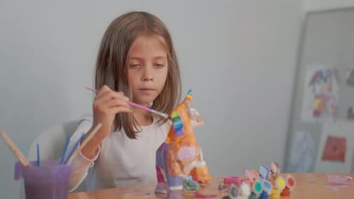 Blondes Mädchen, das zu Hause Gipsfiguren malt und bastelt