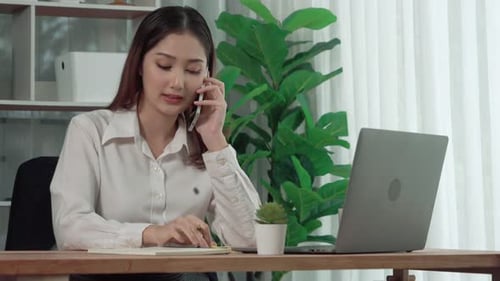 Woman on Phone Taking Notes at Desk