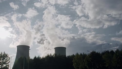 Cooling Towers in Power Plant Generating Steam Against Cloudy Sky