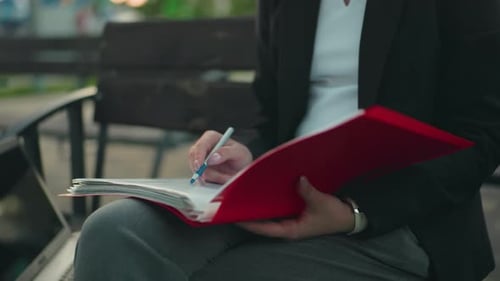 Woman Takes Notes on Bench Using Laptop