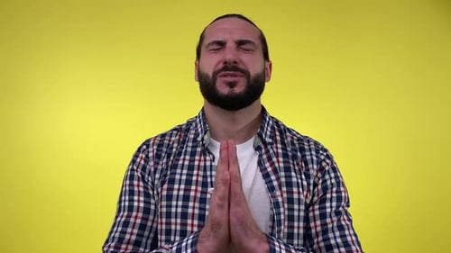 Portrait Bearded Man Closed Eyes Wishing Good Luck Isolated on Yellow