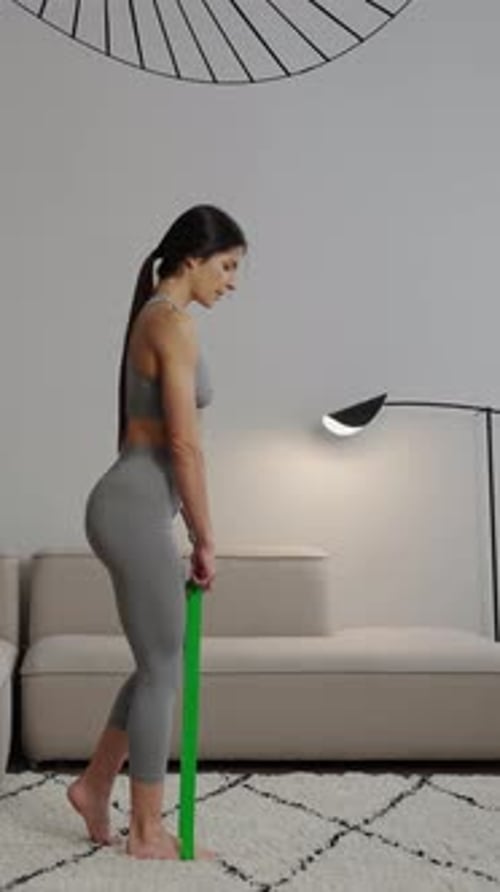 Focused Woman Performing Standing Resistance Band Exercise in Modern Living Room Demonstrating Home