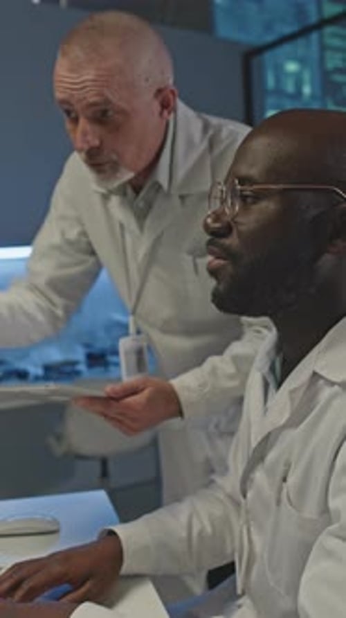 Diversos engenheiros em jalecos de laboratório trabalhando juntos à noite
