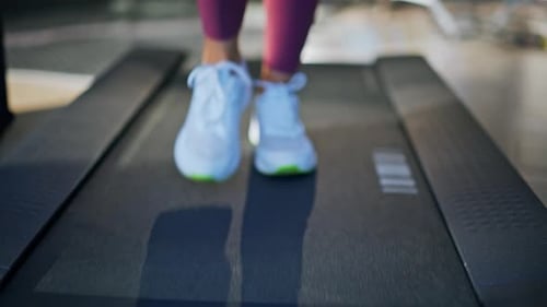 Woman's feet in white running shoes on treadmill