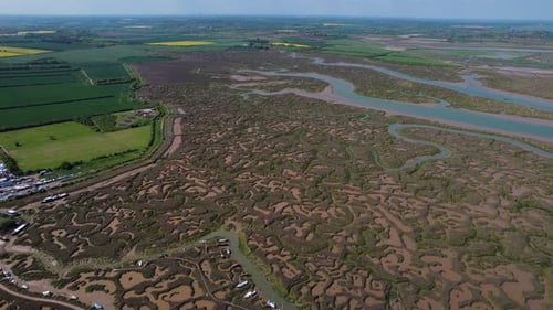 Aerial view above Tollesbury marshland veins and landmark lightship moored on eroded marina estuary