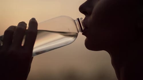 Silhouette of Active Woman Drinking Water at Sunrise