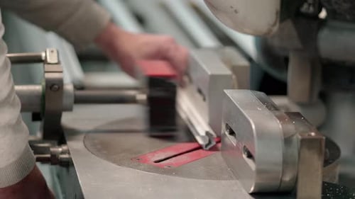 hands of a man cutting aluminum with electric saw inside a window factory