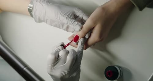 Top View on Manicure Master Hands Applying Red Gel Polish on Client Nail