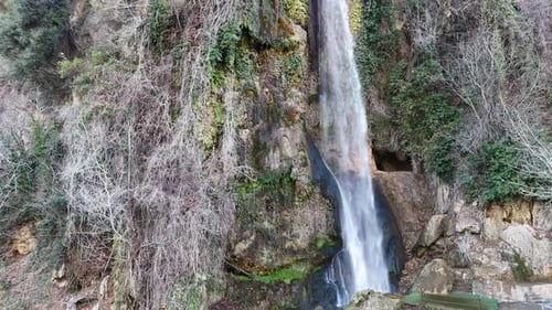 Drone view of a naturally beautiful waterfall flowing from the top of the mountain