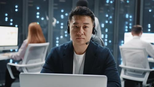 Man wearing headset in server room with laptop