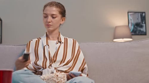 Woman Relaxes on Couch with Phone and Popcorn