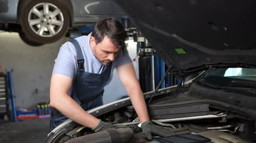 Mechanic repairs car using a tablet for diagnostics